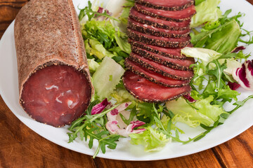 Dry-cured sausage slices and piece of the same sausage
