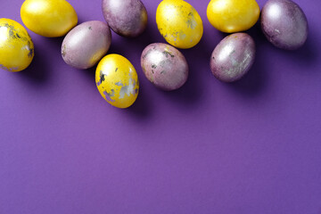 Bright Easter eggs with metallic yellow and purple accents on a vibrant purple background