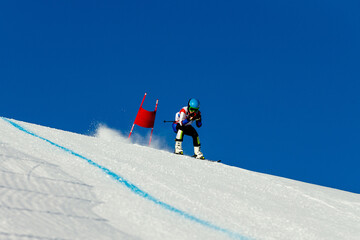skier passes red gate down snow-covered slope during competitive downhill skiing