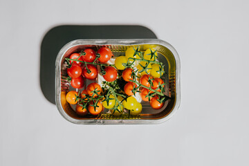 A tray of assorted fruits and vegetables, including tomatoes and grapes. The tray is placed on a...