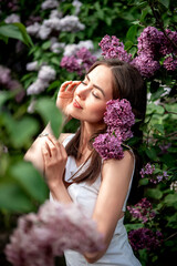 a girl in blueberry flowers, a beautiful young girl in a park with lilac bushes, a girl enjoying nature and the scent of flowers in summer walking in the park