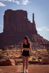 Young female tourist visiting and walking through Monument Valley on vacation on a hot day in the United States.