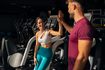 Fototapeta premium Fit Man and Woman High Fiving in Gym Setting