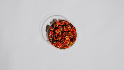 A bowl of food with a white background. The bowl is filled with red food and has a white rim