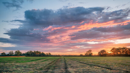Obraz premium Sunset over the field Captivating 4K time lapse majestic sunrise and sunset landscape with stunning natures light and rolling colorful clouds