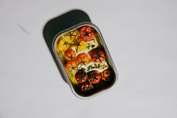 A tray of food with tomatoes and other vegetables. The tray is in a white background. The food...