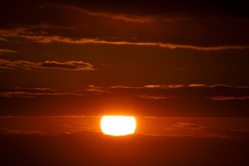 Sunset casts vibrant hues over tranquil horizon with dramatic clouds in the evening sky