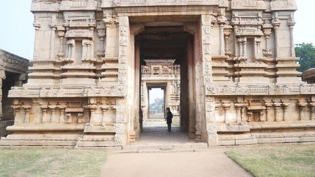 Woman exploring amazing temple complex at Hampi, world famous unesco site. Tourist walking among ruins stone walls gateways in Karnataka, India
