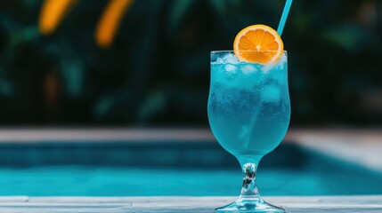 A refreshing blue cocktail garnished with an orange slice, placed near a pool, surrounded by lush greenery.