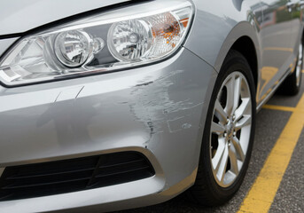 Closeup of car front bumper with scratches and scuff marks.