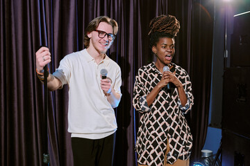 Musicians standing on stage holding microphones while engaging audience with their performance...