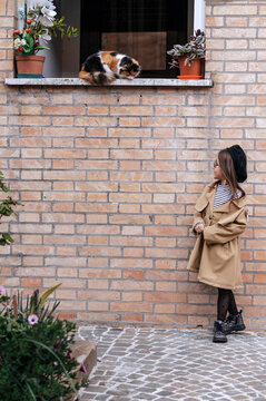 Girl in Civitanova observing a cat on a windowsill