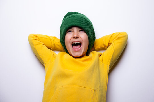 Child expressing joy in yellow hoodie and green beanie