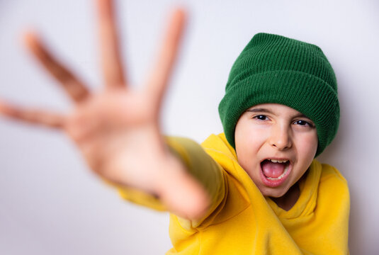 playful child reaching outward wearing green hat