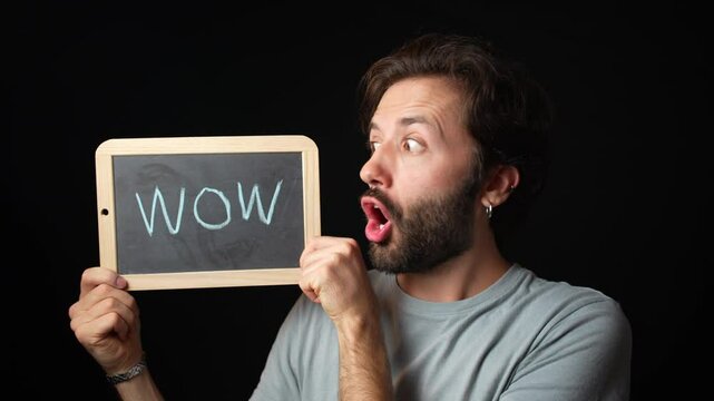 Surprised caucasian Man holding a Chalkboard with the Handwritten word  "wow"