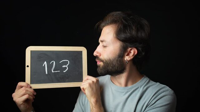 Caucasian Man looking at Chalkboard with the Handwritten word  "123"