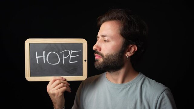 Happy caucasian Man holding a Chalkboard with the Handwritten word  "hope"