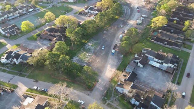 Row of end dump, round bottom heavy-duty hauling trucks along Antoine Dr residential street in North Houston, moving aggregate and construction materials for stormwater detention basins project