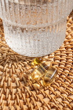 Omega 3 and vitamin D3 supplements on a rattan tray with water