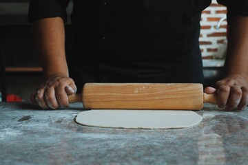 Young chef man preparing pizza in kitchen