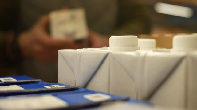 Close-up of many milk cartons and a customer takes one