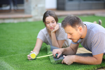Couple at home installing artificial grass in the garden