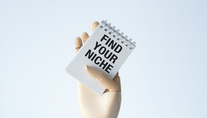 A hand holding a notebook with the words Find Your Niche written on it