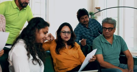 Indian Asian young entrepreneur startup team brainstorming ideas or planning strategies in an informal meeting while sitting on a sofa together with a laptop and documents in a modern office