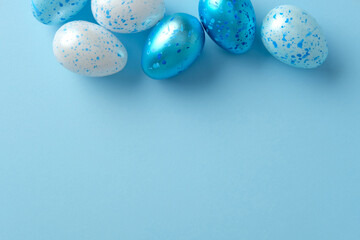 Vibrant Easter eggs with blue and white speckles on a pastel blue background
