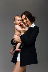 Studio portrait of a mother in black jacket and white shirt with her newborn naked baby boy. Happy motherhood concept