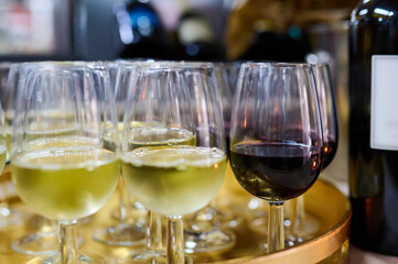 Close-up of glasses filled with white and red wine on a golden tray, ready for serving at an elegant event or celebration