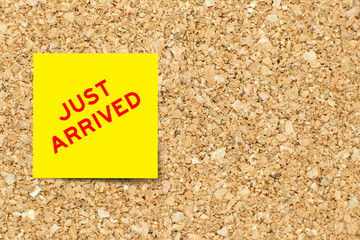 Yellow note paper with word ust arrived on cork board background with copy space