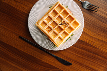 Belgian waffle sandwich with green lettuce, tomato and cheese