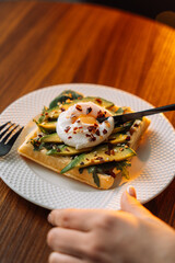 waffles with poached egg avocado on plate on wooden background