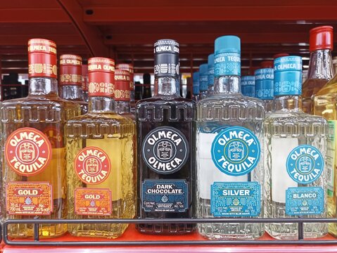 Variety of olmeca tequila bottles displayed on store shelf in different flavors and colors