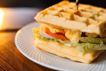 Fresh homemade belgian waffle sandwich with green lettuce, Scrambled eggs, tomato on wooden table