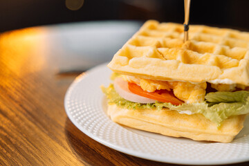 Fresh homemade belgian waffle sandwich with green lettuce, Scrambled eggs, tomato on wooden table