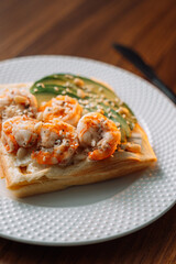 Shrimp waffles on a fork at a wooden table