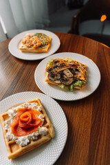 Different types of salty waffles with egg, mushrooms, salmon, mushrooms for breakfast