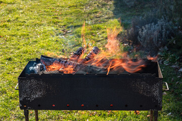 a metal grill with burning firewood for a bbq outdoors