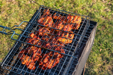 close up view of chicken legs in a grill grate above charcoal grill