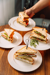 Different triangle sandwiches in hands on brown table