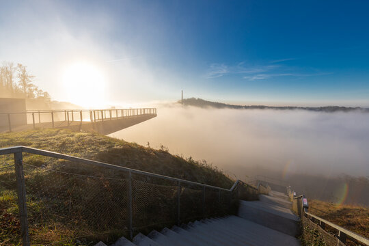 A misty morning on the top of one of the rolling hills in Maastricht where the valley is being blocked by fog, creating a magical atmosphere and idyllic view over the former marl quarry and industry