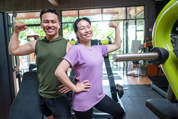 Obraz premium Chinese east asian woman and indonesian southeast asian man working out together at the gym. Fitness exercise and healthy lifestyle concept