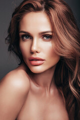 Naklejka premium Fashion beauty portrait of young brunette woman with evening stylish makeup and perfect clean skin. Sexy model with curly hairstyle posing in studio