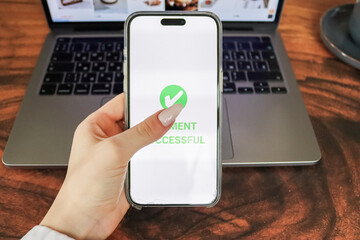 A smartphone screen displays a successful payment message, while a laptop with an open shopping...