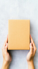 Fototapeta premium person holding plain brown delivery box with both hands, showcasing concept of online shopping and delivery