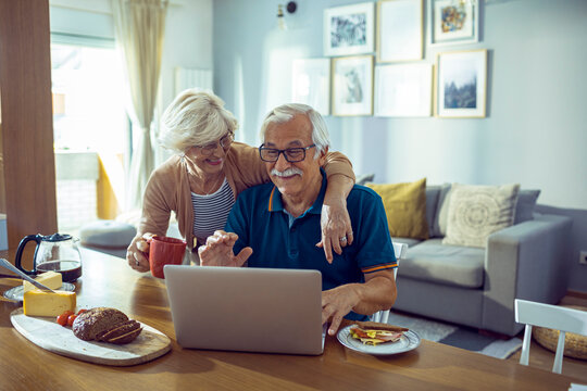 Senior couple managing finances and bills at home with laptop