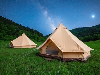 Tranquil glamping tents under a starlit sky in a lush field surrounded by rolling hills offer the perfect serene escape