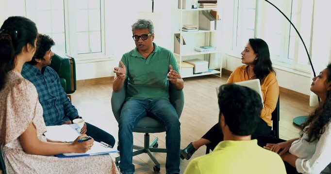 Indian Asian group in a business meeting, discussing mental health and support in a diverse office setting. Team communication, collaboration, and wellness in a professional conference room